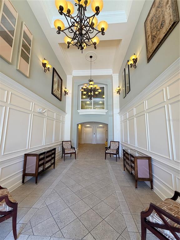 A formal hallway features wainscoting, two chandeliers, matching sideboards, and chairs on tiled flooring — 3368 ROBERT TRENT JONES DRIVE UNIT 10408, ORLANDO, FL