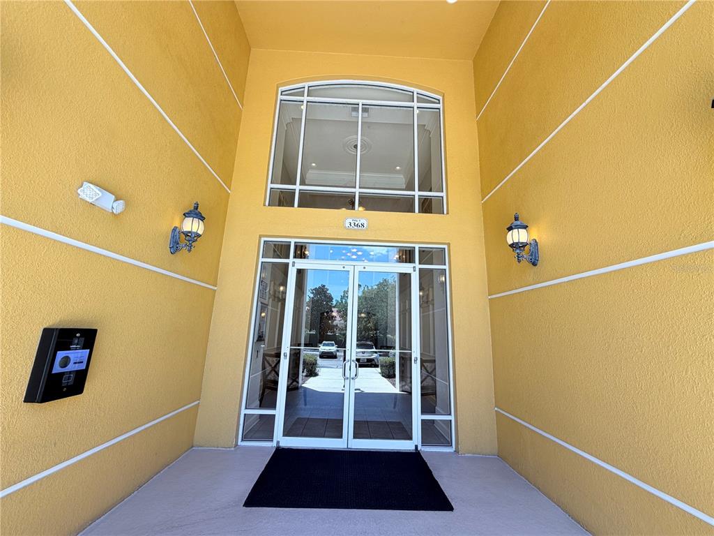 The exterior entrance features double glass doors, a large arched window, and yellow stucco walls — 3368 ROBERT TRENT JONES DRIVE UNIT 10408, ORLANDO, FL