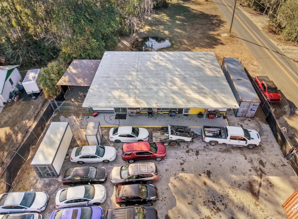 An aerial view shows a commercial property with multiple buildings, a fenced car lot, and parking — 2310 SE 59TH STREET, OCALA, FL