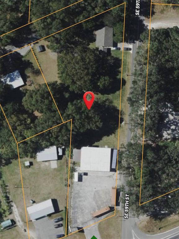 An aerial view shows several buildings, a parking area with many vehicles, and surrounding trees — 2310 SE 59TH STREET, OCALA, FL