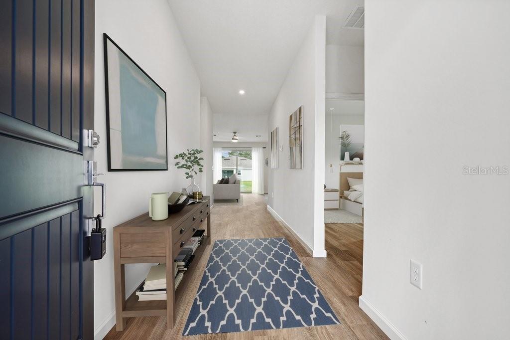 A bright entryway features a wooden console table, a blue patterned rug, and light flooring — 34 BRIAN LANE, PALM COAST, FL
