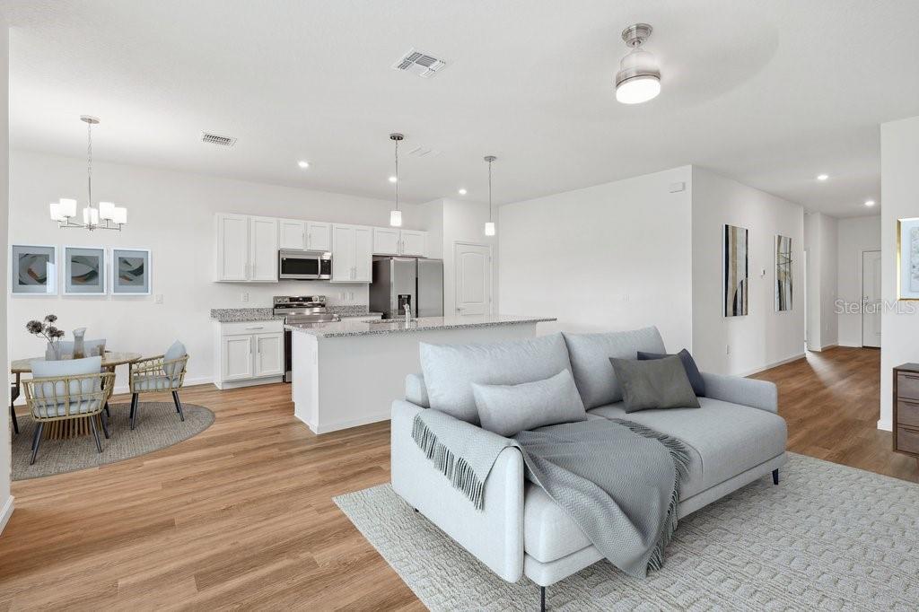 An open-concept kitchen and living area with white cabinets, stainless appliances, and light wood flooring — 34 BRIAN LANE, PALM COAST, FL