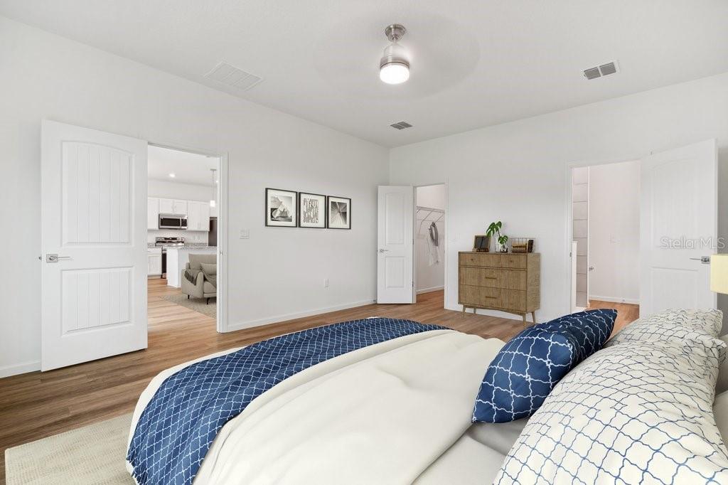 A bedroom with white walls, wood-look flooring, a bed, and doorways leading to other rooms — 34 BRIAN LANE, PALM COAST, FL