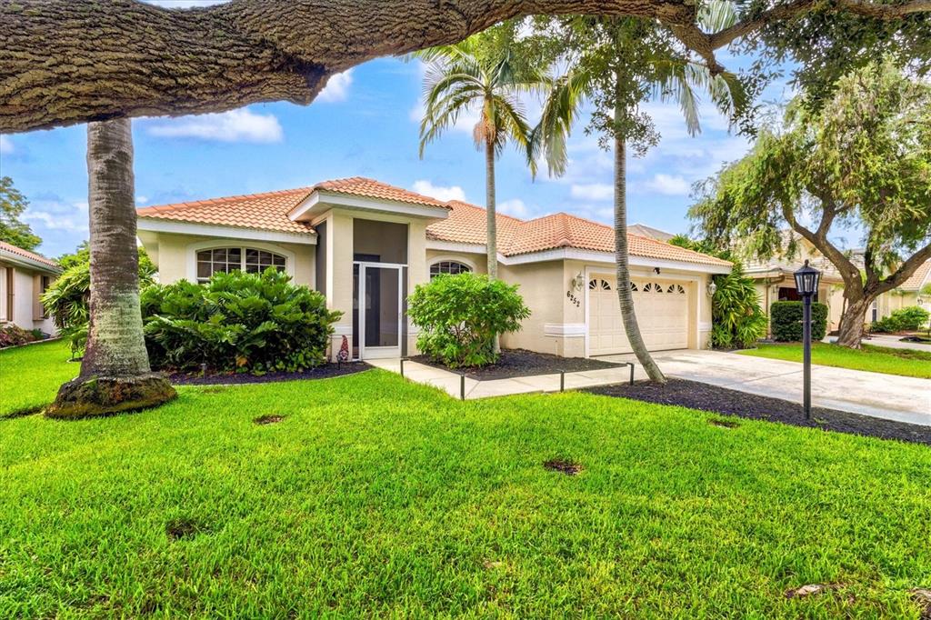 The exterior of a single-story house features a screened entryway, landscaping, and a tiled roof — 6252 DONNINGTON COURT, SARASOTA, FL