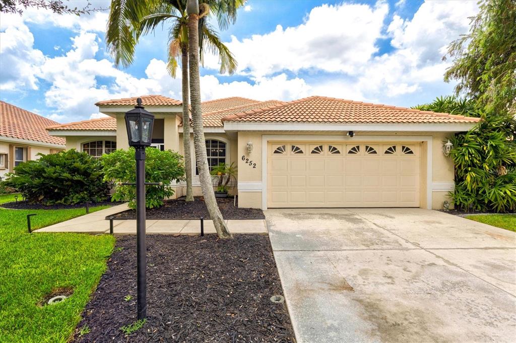 A dining room features a wooden table, upholstered chairs, a leather bench, and wall art — 6252 DONNINGTON COURT, SARASOTA, FL
