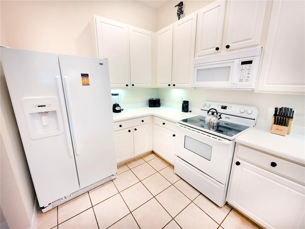 A kitchen with white cabinets, white appliances, and light-colored tile flooring — 716 LUCAYA LOOP UNIT B1/U716, DAVENPORT, FL