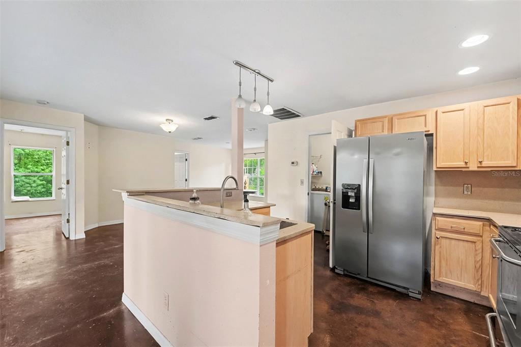 A kitchen with light wood cabinets, stainless steel appliances, and dark concrete flooring — 7295 CENTERWOOD AVENUE, SPRING HILL, FL