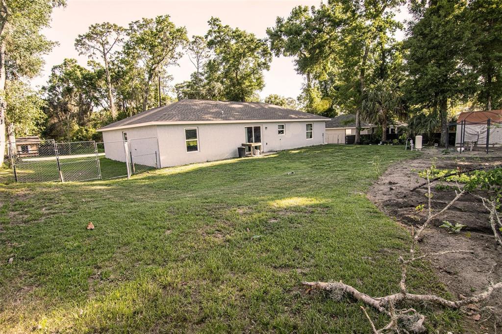 A view of the back of a single-story house with a large, grassy backyard — 3661 SE 131ST PLACE, BELLEVIEW, FL