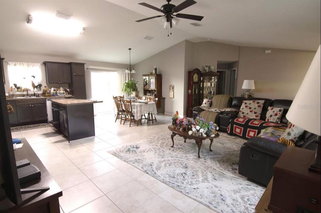 An open-concept living room and kitchen with tile flooring, dark cabinetry, and a ceiling fan — 3661 SE 131ST PLACE, BELLEVIEW, FL