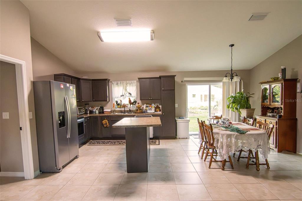 A kitchen with dark cabinets, a central island, and an adjacent dining area with tile flooring — 3661 SE 131ST PLACE, BELLEVIEW, FL