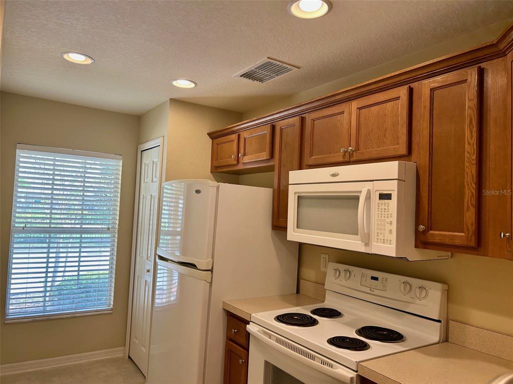 A kitchen features wooden cabinets, a white microwave, a white stove, and a white refrigerator — 2078 SUN DOWN DRIVE, CLEARWATER, FL