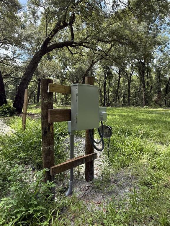 An electrical service panel is mounted on a wooden post structure in a grassy area — 8431 NW 60 AVENUE, CHIEFLAND, FL