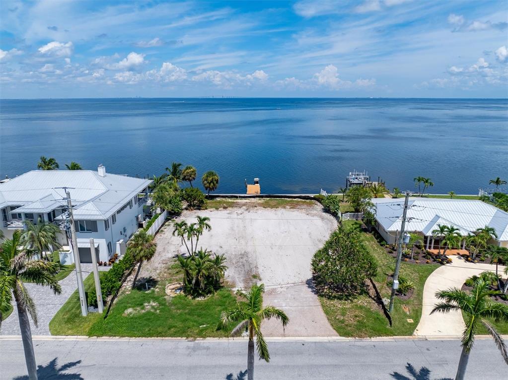 An aerial view of a vacant waterfront lot situated between two residential houses — 659 KEY ROYALE DRIVE, HOLMES BEACH, FL
