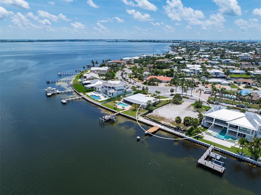 An aerial view shows a vacant waterfront lot situated between two large residential properties — 659 KEY ROYALE DRIVE, HOLMES BEACH, FL