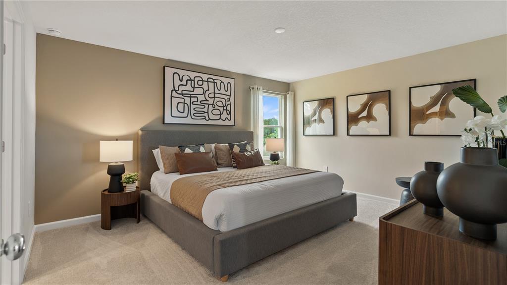A bedroom features a gray upholstered bed, neutral walls, and three pieces of framed wall art — 1564 WILLOW GARDEN LOOP, EUSTIS, FL