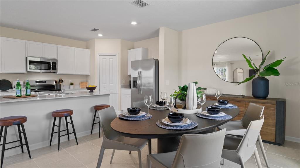 A kitchen with white cabinets and a dining area featuring an oval table and chairs — 1564 WILLOW GARDEN LOOP, EUSTIS, FL