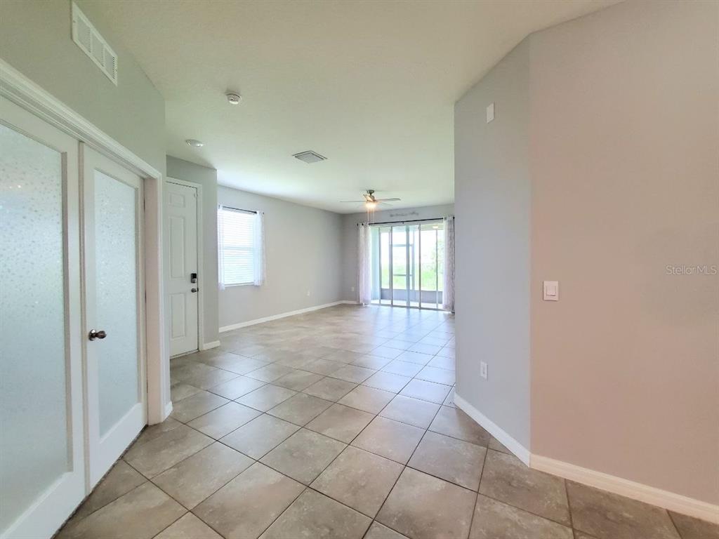 An open-concept living area features light gray walls, tile flooring, and sliding glass patio doors — 31457 MANGO FADE WAY, SAN ANTONIO, FL