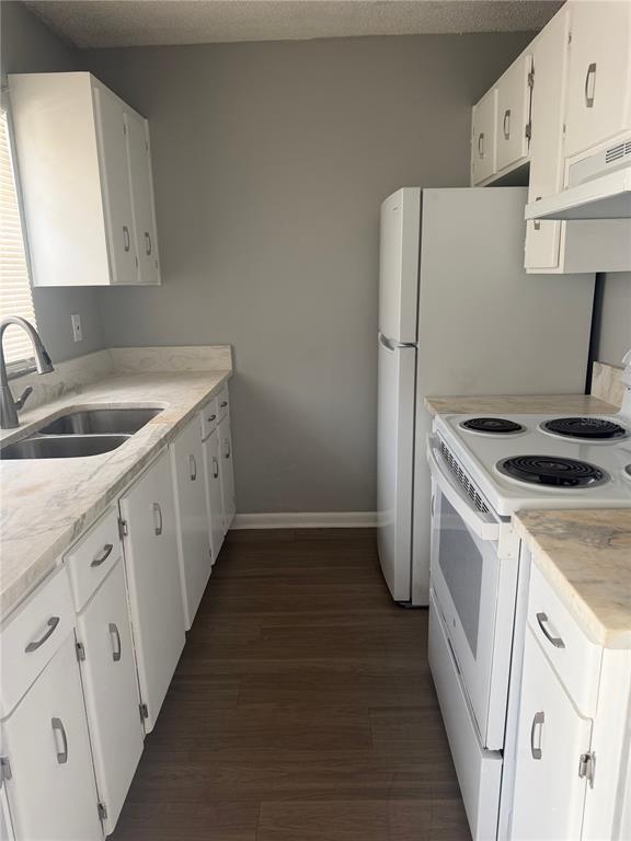A galley kitchen features white cabinets, light countertops, a stainless steel sink, and white appliances — 709 OCEANSIDE CIRCLE UNIT 739, RUSKIN, FL