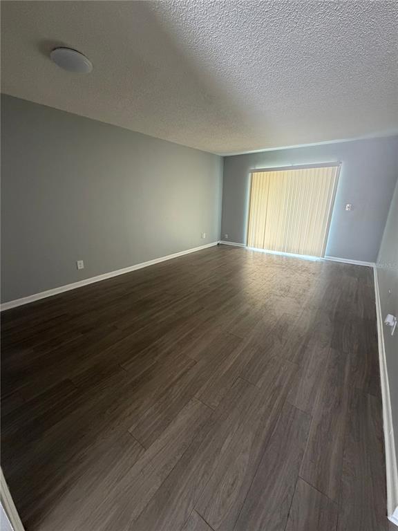 An empty living room features gray walls, wood-look flooring, and a sliding glass door — 709 OCEANSIDE CIRCLE UNIT 739, RUSKIN, FL