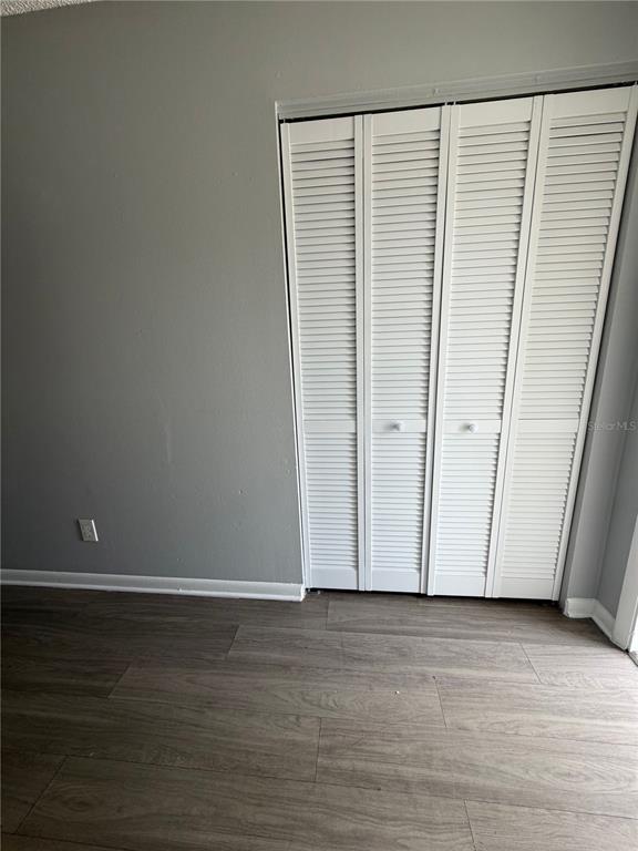 A room with gray walls, wood-look flooring, and white louvered bifold closet doors — 709 OCEANSIDE CIRCLE UNIT 739, RUSKIN, FL