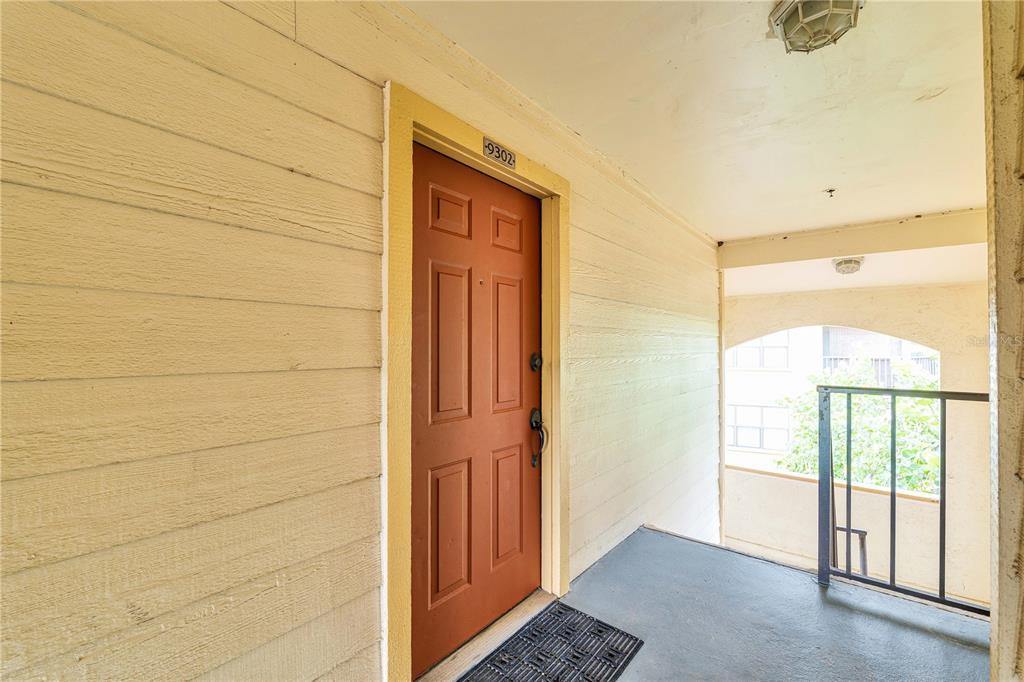A red front door with the number 9302 is set in a beige exterior hallway — 11901 4TH STREET N UNIT 9302, ST PETERSBURG, FL