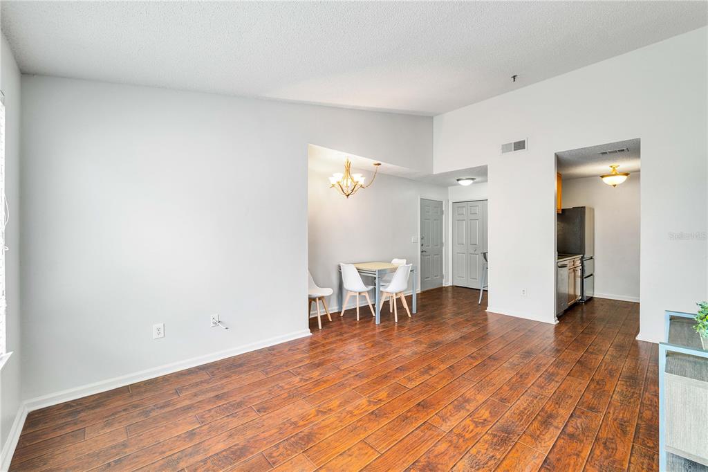 A dining area with a table and chairs sits adjacent to a kitchen with wood-look flooring — 11901 4TH STREET N UNIT 9302, ST PETERSBURG, FL