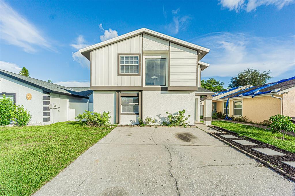 A two-story house with white siding and a concrete driveway under a blue sky — 10305 BRAMBLEWOOD PLACE, TAMPA, FL