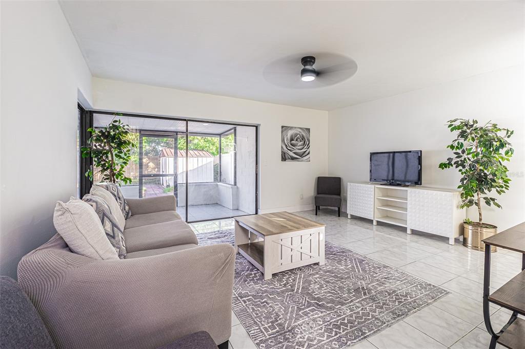 A living room features a gray sofa, a coffee table, a television console, and tile flooring — 10305 BRAMBLEWOOD PLACE, TAMPA, FL