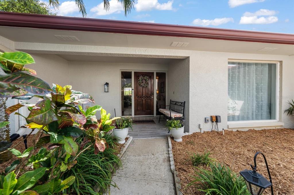 A concrete walkway leads to the front entrance of a house with a wooden door — 2126 EGRET DRIVE, CLEARWATER, FL