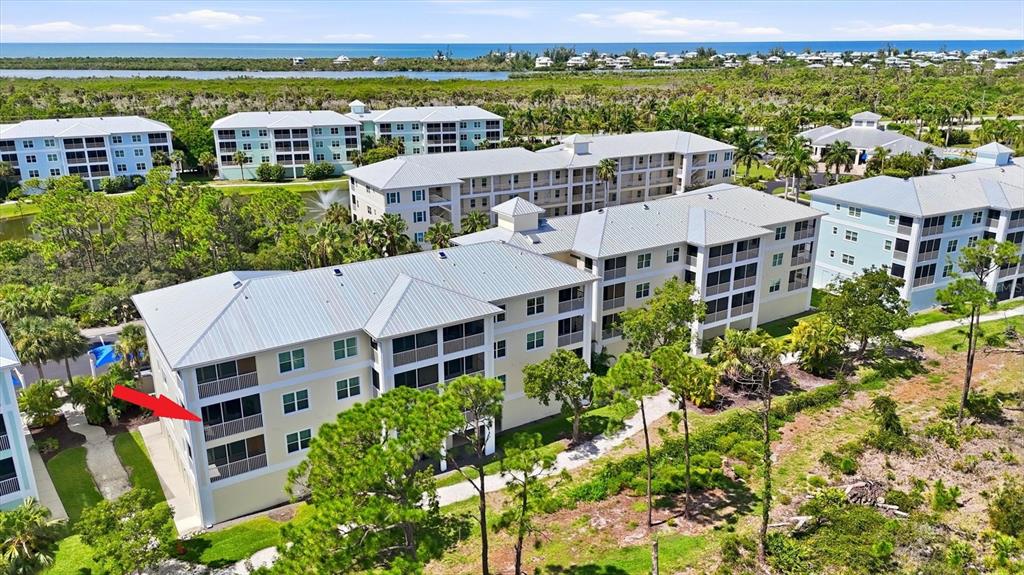An aerial view shows a multi-story residential building with a red arrow pointing to a balcony — 8409 PLACIDA ROAD UNIT 308, PLACIDA, FL