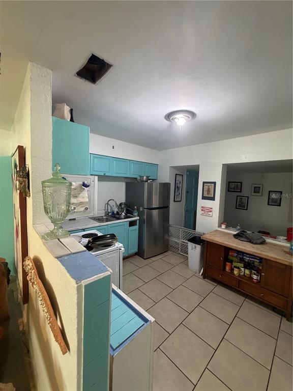 A kitchen features light blue cabinets, stainless steel appliances, and beige tile flooring — 811 28TH AVENUE S, ST PETERSBURG, FL