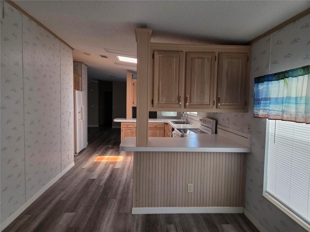 A kitchen with wood cabinets, a breakfast bar, and light-colored wallpaper — 3224 MANATEE ROAD, TAVARES, FL