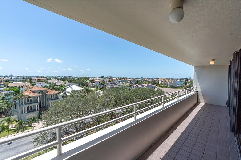 A tiled balcony with a white metal railing overlooks a residential neighborhood and water — 5950 PELICAN BAY PLAZA S UNIT 601, GULFPORT, FL