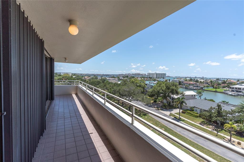 A tiled balcony with a metal railing overlooks a waterway, trees, and distant buildings — 5950 PELICAN BAY PLAZA S UNIT 601, GULFPORT, FL