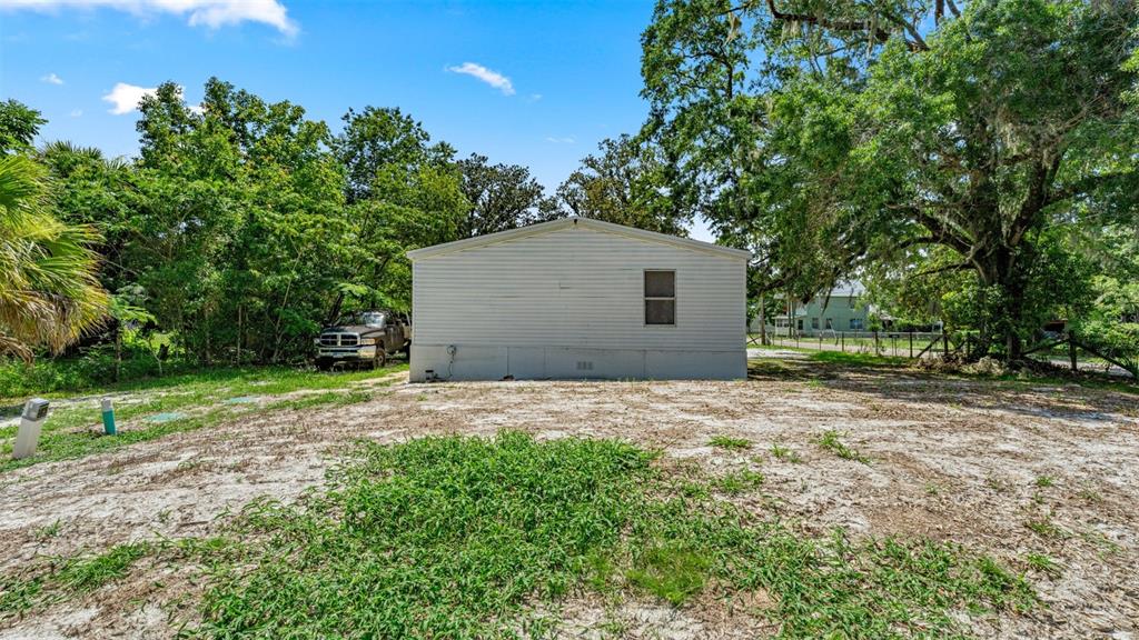 A single-story mobile home with white siding sits on a sandy lot with trees — 10530 PROSPECT AVENUE, HAMPTON, FL