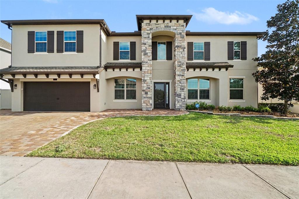 A two-story house with a stone-accented entryway, a two-car garage, and a front lawn — 17987 GOURD NECK LOOP, WINTER GARDEN, FL