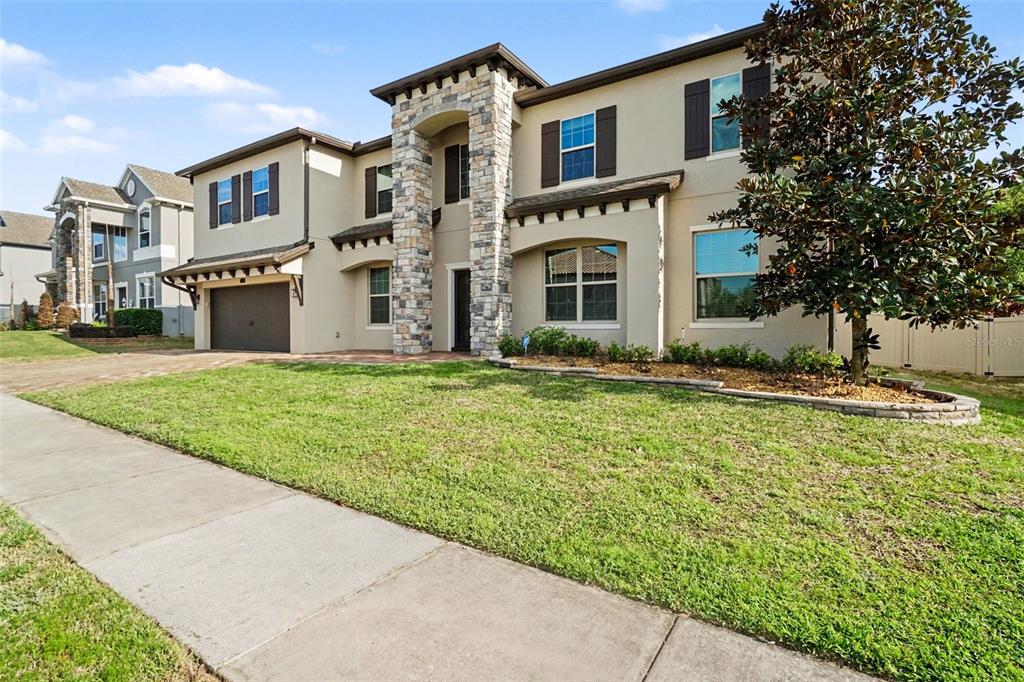 A two-story house with a stone-accented entryway, tan stucco exterior, and a two-car garage — 17987 GOURD NECK LOOP, WINTER GARDEN, FL