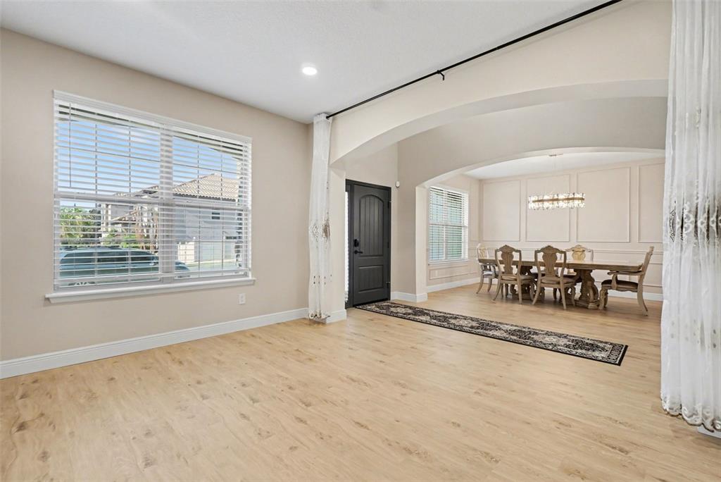 A living area with light wood floors leads to a dining room through an arched opening — 17987 GOURD NECK LOOP, WINTER GARDEN, FL
