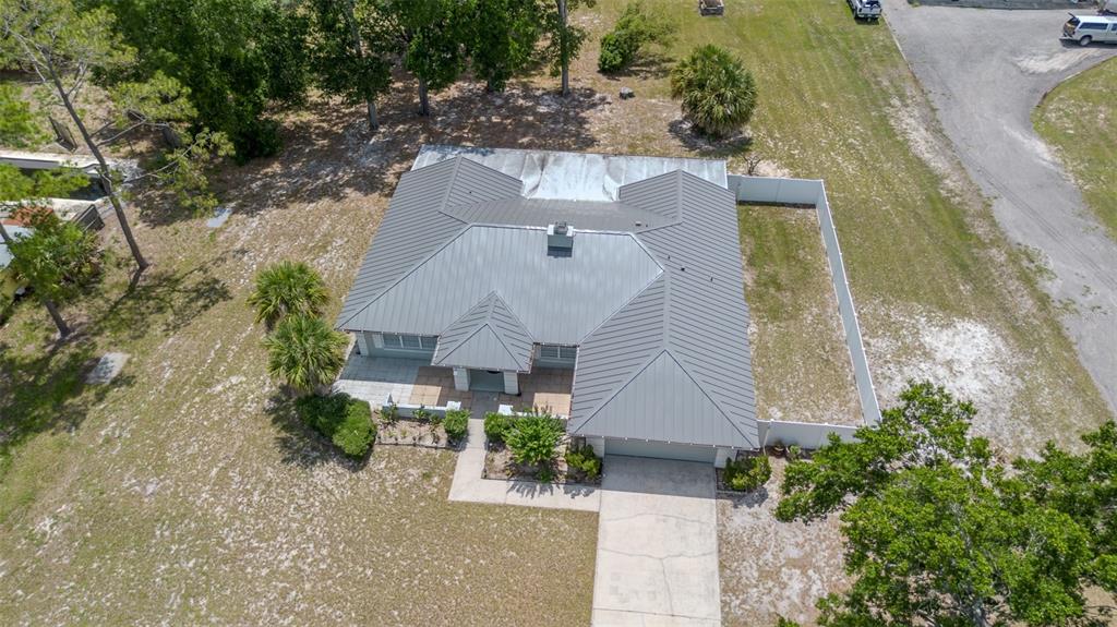 A single-story house with a metal roof, light-colored siding, and a concrete driveway — 1861 CROWLEY CIRCLE E, LONGWOOD, FL