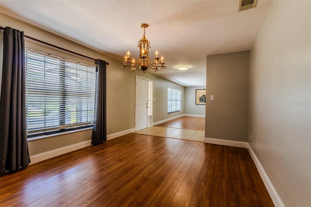 An empty living room features gray walls, wood-look flooring, and a large window with blinds — 1861 CROWLEY CIRCLE E, LONGWOOD, FL