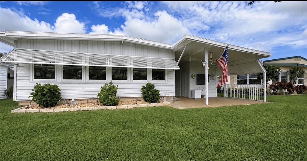 A white mobile home with a front porch, an American flag, and a grassy lawn — 1100 BELCHER ROAD S UNIT 448, LARGO, FL