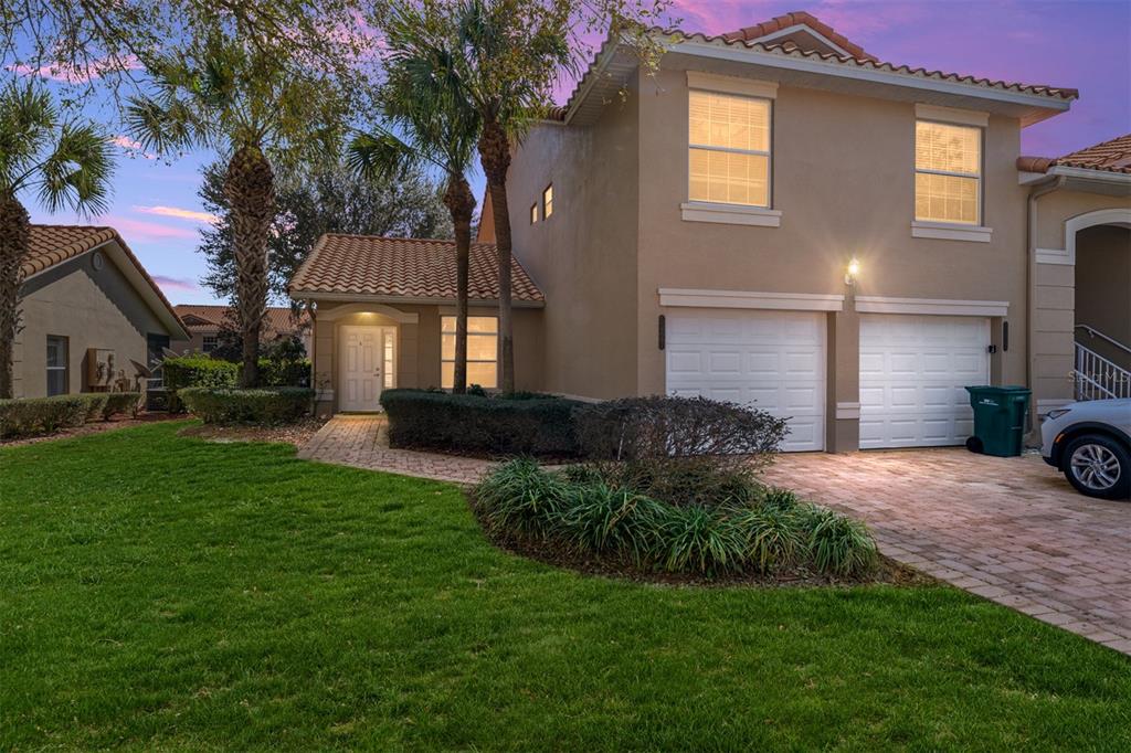 A two-story house with a tan stucco exterior, tile roof, and a two-car garage — 5427 COMPASS POINT UNIT 1, OXFORD, FL