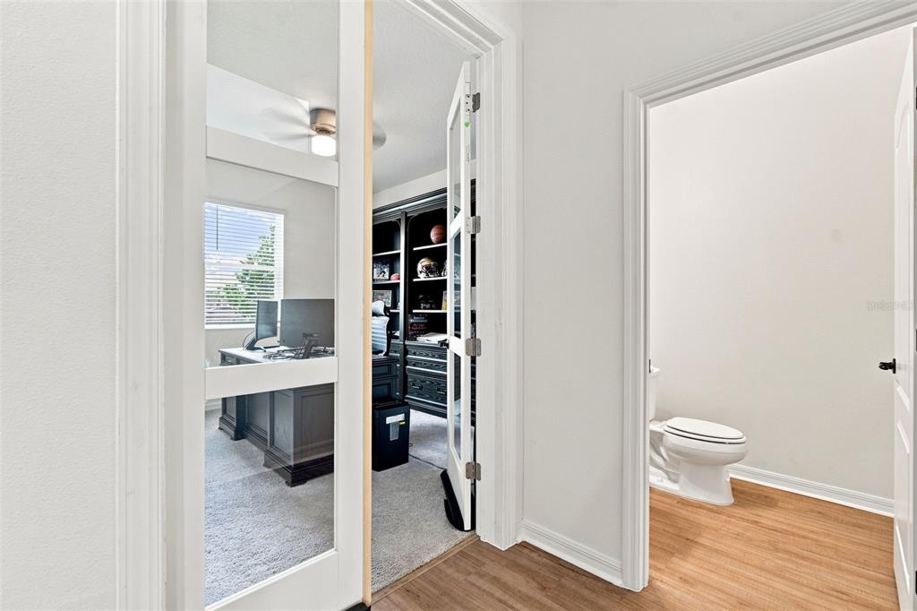 A view through a glass-paneled door into a home office beside a small bathroom — 6473 BURNING OPAL BEND, LAND O LAKES, FL