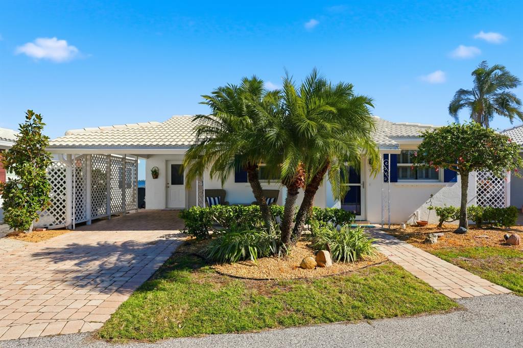 A single-story house with a paved driveway, a carport, and a palm tree in front — 957 SPANISH DRIVE N, LONGBOAT KEY, FL