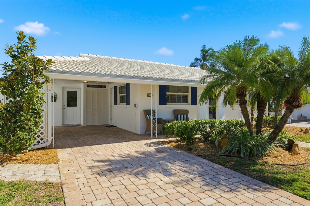 A single-story house with a paved driveway, white exterior, and a palm tree in front — 957 SPANISH DRIVE N, LONGBOAT KEY, FL