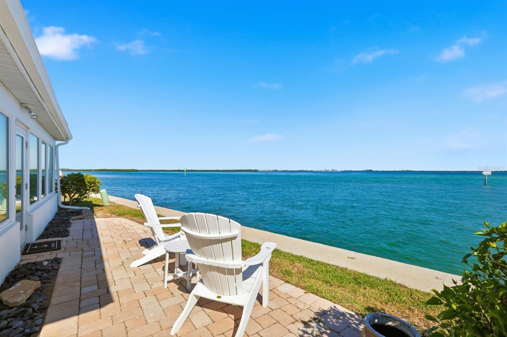 A patio with two white chairs overlooks a blue body of water under a clear sky — 957 SPANISH DRIVE N, LONGBOAT KEY, FL