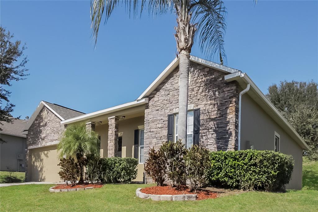 A single-story house with stone veneer siding, a palm tree, and a manicured front lawn — 1117 SPRUCE RIDGE COURT, MINNEOLA, FL
