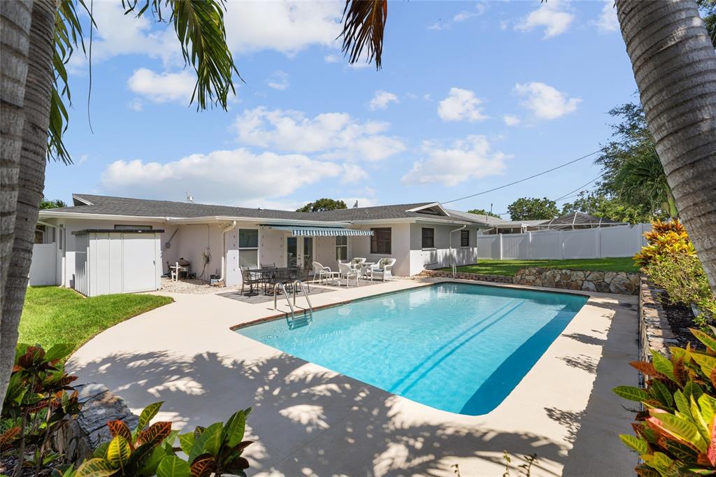 A backyard features a swimming pool, a patio with outdoor furniture, and a white fence — 6249 HILLSIDE AVENUE, SEMINOLE, FL