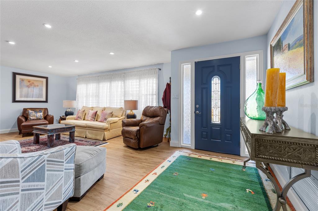 A living room with a blue front door, wood flooring, and a green area rug — 6249 HILLSIDE AVENUE, SEMINOLE, FL