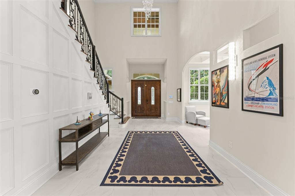 A bright foyer features a high ceiling, a wooden staircase, and a large area rug — 6288 BLAKEFORD DRIVE, WINDERMERE, FL